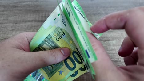 Hands-holding-a-bundle-of-one-hundred-euro-cash,-close-up-video