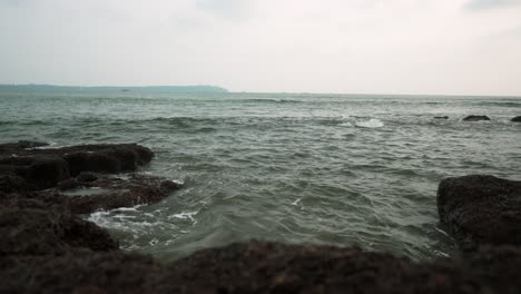 Felsige-Küste-Mit-Blauem-Wasser,-Das-Unter-Einem-Bewölkten-Himmel-Am-Strand,-Indien,-Auf-Die-Felsen-Trifft