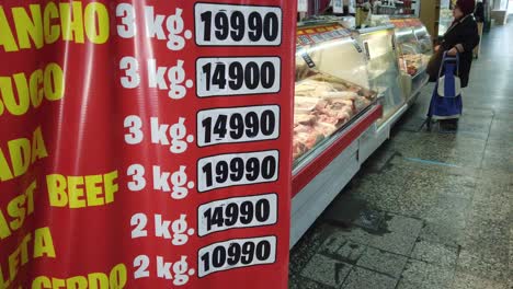 Metzgerei,-Argentinische-Dame-Kauft-Fleisch-Auf-Dem-Markt-Mit-Dem-Verkäufer,-Kühlschränken-Und-Theke