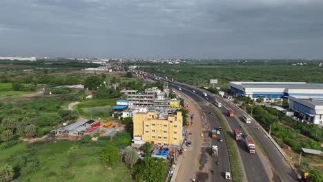 Daytime-view-of-the-Chennai-to-Hosur-highway-passing-through-an-industrial-zone,-with-factories-and-warehouses-visible-along-the-route