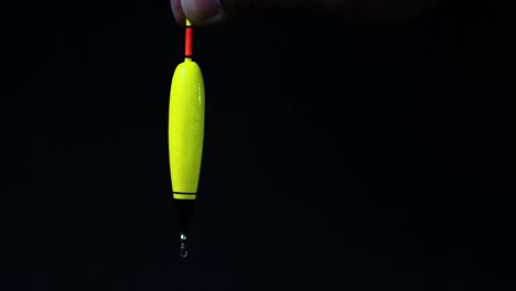 Hand-is-holding-fishing-float-in-black-background