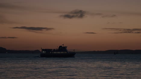 Fähre-In-Der-Abenddämmerung-Als-Silhouette-Vor-Einem-Goldenen-Himmel-über-Ruhigem-Wasser