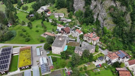 Rothenbrunnen,-switzerland,-showcasing-buildings,-green-areas,-and-mountains,-aerial-view