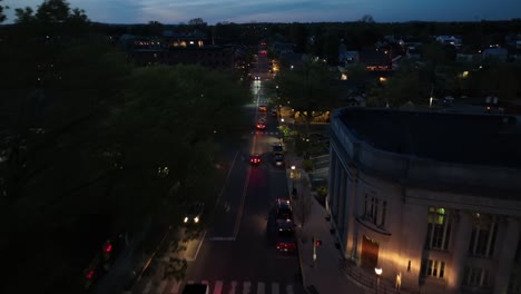 Aerial-flyover-lighting-city-at-night-with-driving-cars-on-main-street