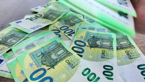 Un-Hombre-Recoge-Billetes-De-100-Euros-Dispersos.