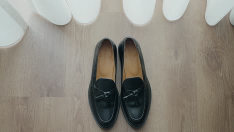 Pair-of-black-leather-shoes-on-a-wooden-floor,-emphasizing-classic-elegance-and-simplicity