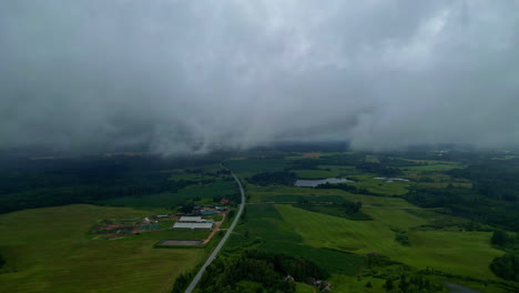 Clouds-and-rain-mist,-low-visibility-in-distance,-aerial-over-rural-land