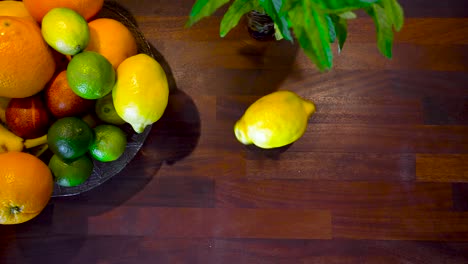 Una-Mano-Girando-Un-Limón-Amarillo-Cítrico-En-El-Sentido-De-Las-Agujas-Del-Reloj-Sobre-Una-Mesa-A-Cámara-Lenta-Y-Retirando-Lentamente-La-Mano