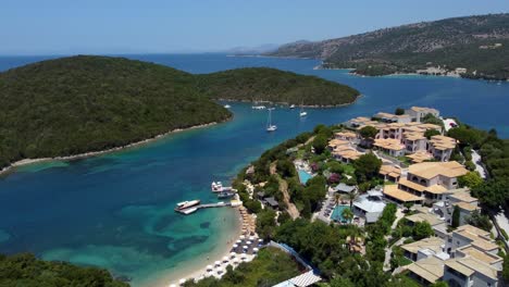 Aerial-Traveling-Panoramic-Shot-of-Syvota-Village,-Beach-and-Boats