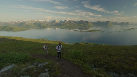 Young-couple-hiking-on-Husfjellet-in-Senja,-Norway-with-trekking-poles