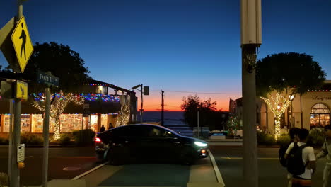 Pan-across-main-road-street-intersection-with-sports-car-driving-through-traffic-stop-Manhattan-Beach-road-nightlife-restaurant-bar-people-California-USA-America