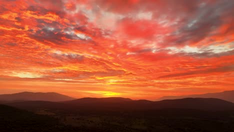 Precioso-Rodaje-Con-Drone-De-Un-Espectacular-Atardecer-Rojo-En-El-Valle-Del-Tiétar-Y-Con-Un-Giro-De-Cámara-Vemos-El-Relieve-De-Las-Montañas-Y-Una-Impresionante-Paleta-De-Colores-Muy-Vivos-En-El-Cielo.