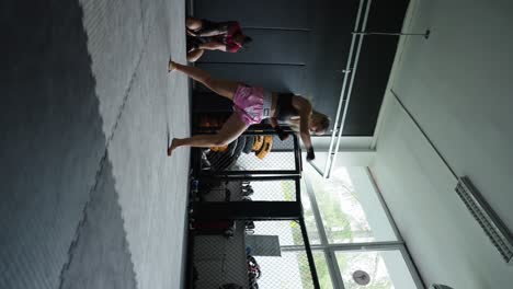 Vertical-shot-of-female-fighter-shadow-boxing-at-indoor-gym,-Czechia