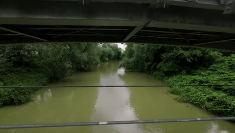 A-serene-river-flows-through-a-lush-green-landscape-with-a-bridge-spanning-the-water