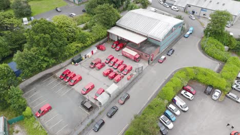 Drone-captures-staff-working-at-the-Royal-Mail-depot,-with-red-delivery-vans-and-bustling-activity,-Tavistock,-Devon,-UK,-June-2024