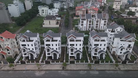 Una-Hilera-Recién-Construida-De-Grandes-Casas-Blancas-Idénticas-De-Estilo-Villa-De-Varios-Pisos-A-Lo-Largo-De-Una-Carretera-Suburbana