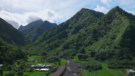 Towering-mountain-volcano-peaks-valley-rivers-Teahupoo-town-Tahiti-French-Polynesia-Moorea-Papeete-aerial-drone-stunning-island-late-morning-afternoon-blue-sky-daytime-sunny-clouds-backward-pan-up