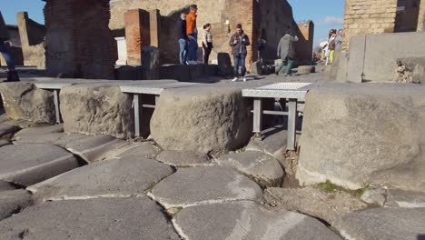 People-discovering-ancient-zebra-crossing-footpath-with-stepping-stones-in-the-streets-of-Pompeii---Naples,-Italy