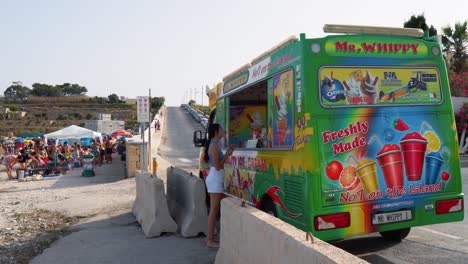 Junges-Maltesisches-Mädchen-Kauft-Im-Sommer-Ein-Getränk-Vom-Beliebten-Mr-Whippy-Eiswagen-Am-Strand-Von-Ghar-Ahmar-Bay