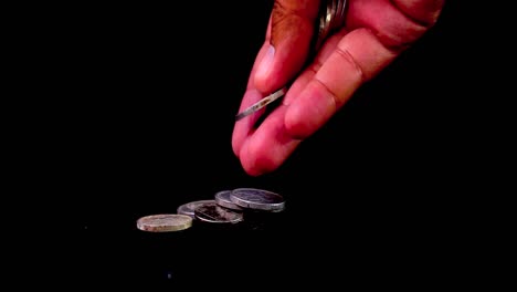 Close-up-shot-of-hand-counting-coin-money-one-by-one-on-black-background