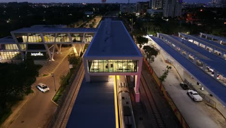 Aerial-flyover-new-developed-modern-train-station-with-arrived-train-on-track-at-night