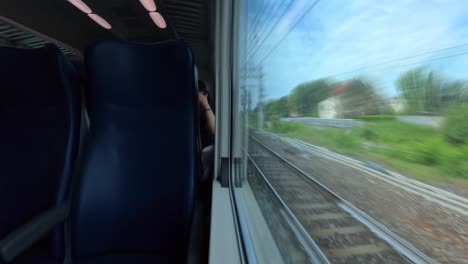 Hyperlapse-of-view-from-train-interior-looking-out-window-at-station-and-scenery