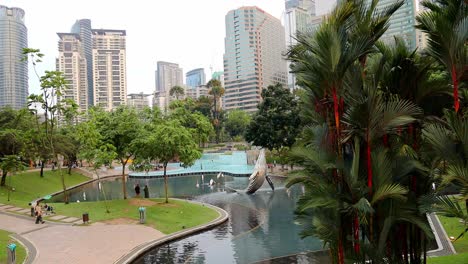 Whale-statute,-trees-and-swimming-area-with-office-buildings-in-background-at-Suria-KLCC-Park-in-Kuala-Lumpur,-Malaysia