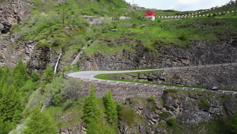 Luftaufnahme-Einer-Bergstraße,-Die-Sich-Durch-üppiges-Grünes-Gelände-Windet-Und-Einen-Atemberaubenden-Blick-Auf-Die-Natürliche-Landschaft-Bietet,-Während-Ein-Auto-Die-Malerische-Route-Entlang-Fährt