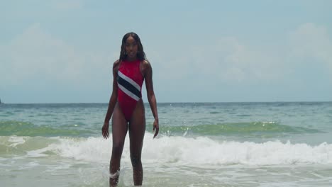 On-a-north-coast-beach-in-Trinidad,-a-young-girl-wearing-a-Trinidad-flag-bikini-enjoys-the-Caribbean