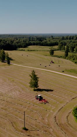 Vertical-video-of-Tractor-collecting-and-baling-hay-rolls