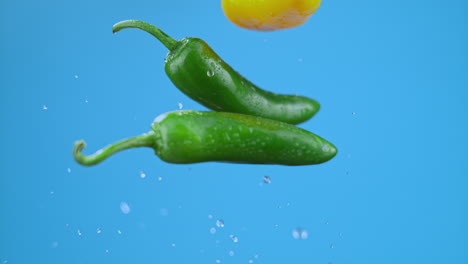 Yellow,-green-chili-bell-peppers-launched-in-air-with-water-droplets,-vegetables-for-cooking