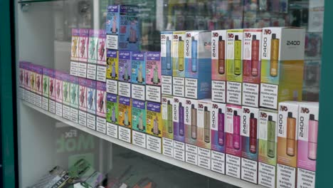 Multicoloured-vapes-on-display-for-sale-in-shop-window,-showing-various-brands-and-flavors,-Exeter-Devon-UK,-June-2024