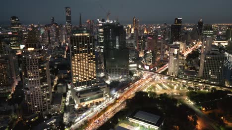 Bangkok-Business-District-at-night-skyline,-aerial-drone-fly-illuminated-town