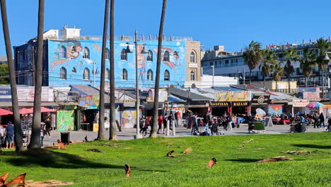 Querformat-Von-Menschen,-Die-Auf-Der-Promenade-Des-Venice-Beach-Boulevard-Mit-Ladengebäuden-Und-Palmen-Spazieren-Gehen,-Los-Angeles,-Amerika,-USA,-Tourismus