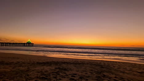 Lebendiger-Sonnenuntergang-über-Einem-Ruhigen-Strand-Mit-Einem-Pier-In-Der-Ferne