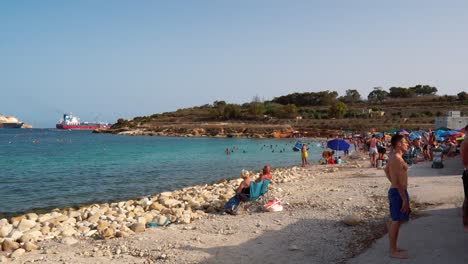 Maltese-people-and-families-enjoy-the-summer-sunbathing-and-swimming-in-the-Mediterranean-Sea-at-Ghar-Ahmar-Bay-in-Marsaxlokk