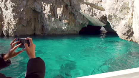 Mujer-Tomando-Una-Fotografía-De-La-Gruta-Verde,-También-Conocida-Como-La-Gruta-Esmeralda,-La-Gruta-Verde,-En-La-Costa-De-La-Isla-De-Capri-En-La-Bahía-De-Nápoles,-Italia