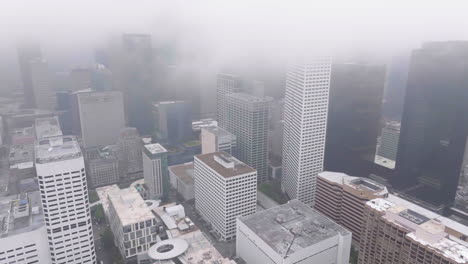 Aerial-view-flying-through-the-fog-covered-downtown-of-Houston-city,-Texas,-USA