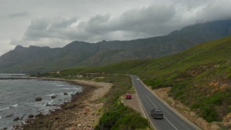 Dron-Siguiendo-A-Un-Automóvil-Que-Conducía-Por-Una-Pintoresca-Carretera-Costera-En-Western-Cape