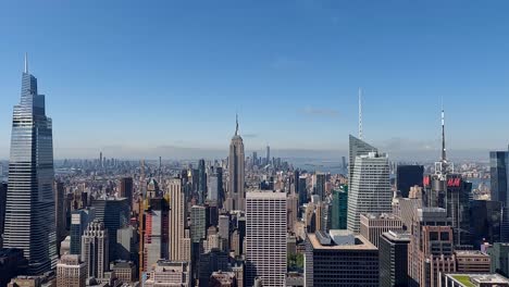 Die-Kamera-Dreht-Sich-Und-Zeigt-Die-Skyline-Der-Stadt-Vom-Rockefeller-Center-Und-Bewegt-Sich-In-4K-Am-Empire-State-Building-Vorbei