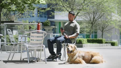 Ein-Mann-Und-Sein-Hund-Sitzen-Gemütlich-Draußen-Und-Checken-Ihr-Telefon