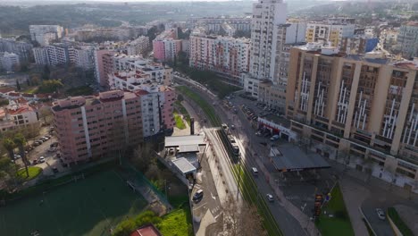 Aerial-view-following-the-Metro-Transportes-do-Sul-tram-in-sunny-Almada,-Portugal