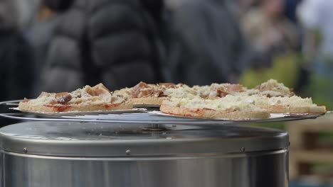 cheese-and-ham-sandwiches-on-an-aluminium-turntable,-people-in-a-blurred-background