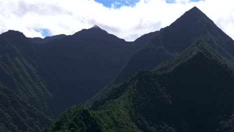 Towering-mountain-volcano-peaks-valley-Teahupoo-Tahiti-French-Polynesia-Moorea-Papeete-aerial-drone-parallax-late-morning-afternoon-daytime-sunny-clouds-stunning-island-scenery-slowly-circle-right