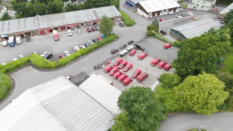 Aerial-view-of-the-Royal-Mail-depot-with-red-postal-vehicles-and-surrounding-buildings,-showcasing-logistics-operations,-Tavistock,-Devon,-UK,-June-2024