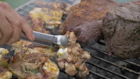 Close-shot-of-two-people-flipping-and-roasting-the-meat-on-barbecue