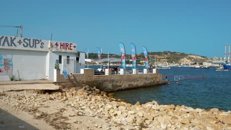 Maltesische-Kinder-Springen-Von-Der-Terrasse-Eines-Lokalen-Restaurants-In-Der-Nähe-Des-Kraftwerks-Delimar-In-Der-Bucht-Von-Ghar-Ahmar-In-Marsaxlokk-Ins-Meer