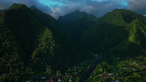 Teahupoo-Tahiti-French-Polynesia-aerial-drone-view-sunset-moody-light-towering-mountain-peaks-valley-town-villageincredible-dark-clouds-island-landscape-Moorea-Bora-Bora-Papeete-forward-pan-up