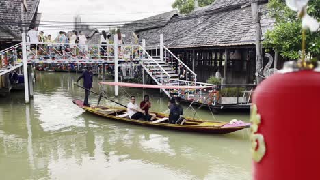 Ein-Boot-Mit-Schwimmendem-Markt-Fährt-Durch-Den-Kanal-Und-Ein-Händler-Verkauft-Traditionelles-Thailändisches-Essen-An-Touristen,-Die-Den-Schwimmenden-Markt-Besuchen