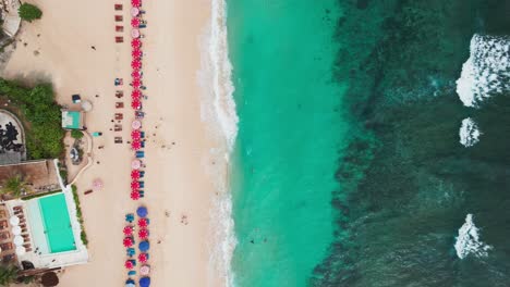 Top-down-view-of-Melasti-Beach-with-sunbeds-and-beautiful-ocean-in-Uluwatu-Bali